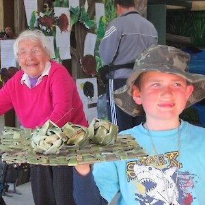 Liam shows off some flax toys for the kaka with Marjorie looking on