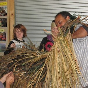 Starting to clothe the frame with tussock and cabbage tree leaves